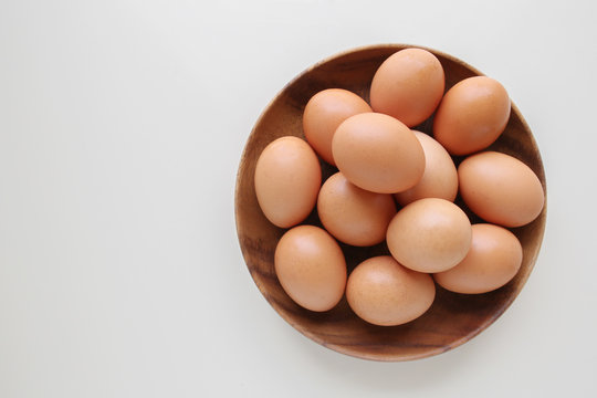 Eggs in wooden bowl on white copy space background