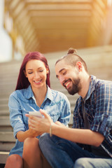 Beautiful young couple looking at the mobile phone together whil