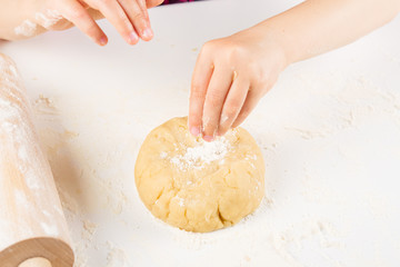 Children's hands knead the dough for baking cookies