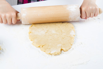Fototapeta na wymiar Detail of children hands kneading dough with wooden roller pin