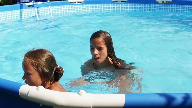 Weekend. Swimming pool. Two cute young girls swimming in a pool. Slow motion. HD