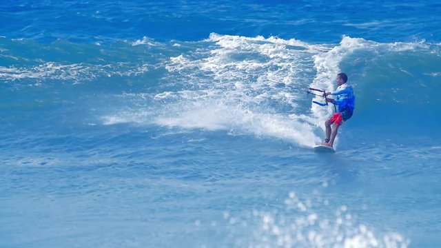 Tracking video of young male surfer sportsman enjoing kitesurfing in ocean