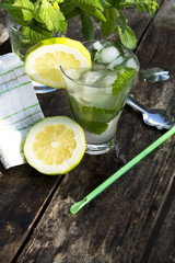 Summer mojito lemonade drink with lime, lemon and mint on wooden background