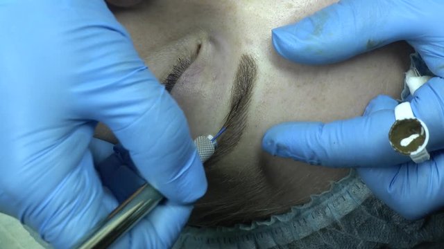 Microblading procedure. Master works with the eyebrows. Semi-permanent make-up.