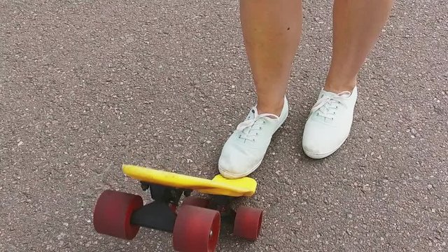 teenage girl toot putting short skateboard on end