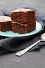 Brownie stack. Chocolate cake in turquoise plate on black table. Homemade pastry for dessert.