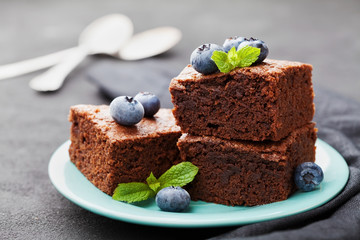 Brownie stack decorated blueberries and mint leaves. Chocolate cake in turquoise plate on vintage...