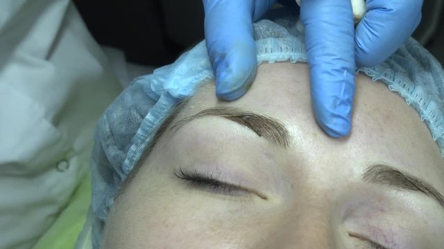 Microblading procedure. Master works with the eyebrows. Semi-permanent make-up.