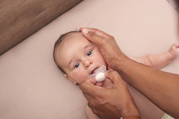 Interracial father calming his baby with a pacifier