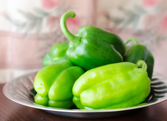 Green paprika / pepper on metal plate and wooden broun table. Cl