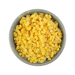 Cooked yellow split peas in an old stoneware bowl top view isolated on a white background.
