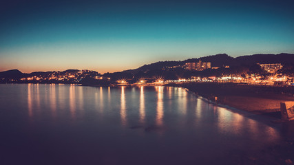 Early evening lights reflecting on ocean at resort
