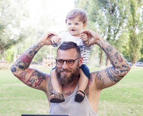 tattooed dad have fun with his son and laptop