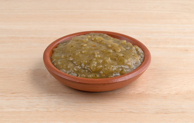 Bowl of culantro cooking sauce on a wood table
