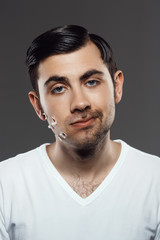 Obraz premium Displeased young man after shaving over grey background.