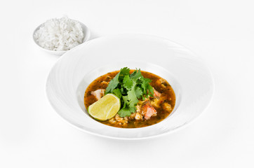 Crab with chili sauce, lime, parsley and rice on a plate on a white background