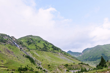 Photo of green capra peak, a small river and a road in fagaras mountains, Romania.