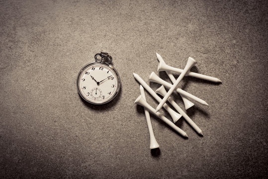 Golf Pegs And Old Watch On Stone Table. Sport Still Life. Concept Of Time, Deadline And Winning.