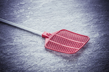 Fly swatter on stone table. Concept of exterminating bugs and insects.