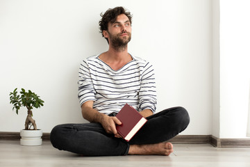 man reading a book and standing on the floor