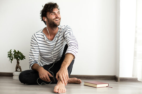 young man sitthing on the floor with headsets in his ears and wi