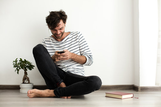 young man sitthing on the floor with headsets in his ears and wi