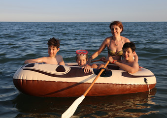 Obraz premium three brothers with mom on the dinghy sailing on the sea