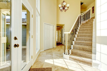 Bright creamy tones entryway with staircase and  tile flooring.