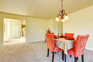 Spacious creamy tones interior of dining room with red chairs.