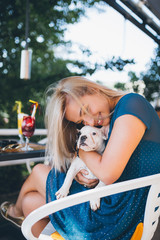 Young blond girl in cafeteria holding adorable French bulldog puppy.