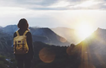 Foto op Canvas Hipster young girl with backpack enjoying sunset on peak of foggy mountain. Tourist traveler on background view mockup. Hiker looking sunlight flare in trip Spain. Picos de Europa. Journey concept © A_B_C