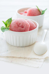 Watermelon sorbet ice cream in bowl on white wooden background