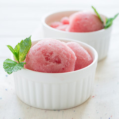 Watermelon sorbet ice cream in bowl on white wooden background