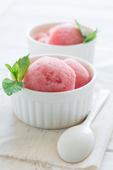 Watermelon sorbet ice cream in bowl on white wooden background