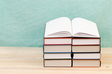 Open book, stack of hardback books on wooden table. Back to school. Copy space