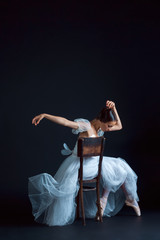 Portrait of the classical ballerina in white dress on black background