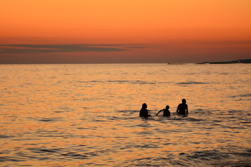 The family silhouette on the sea in sunset.