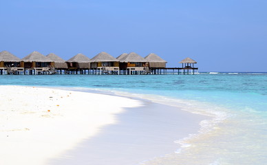 Maldivian beach with white sand, azure water and wooden villas