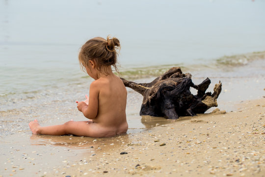 naked little girl plays in the sea, beautiful beach