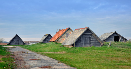 Typical rustic farm house in a village in Belarus. Wooden low sheds with pitched wooden and  tiled roof.