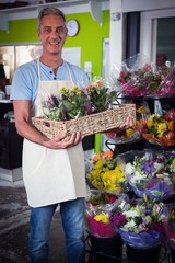 Male florist carrying plant pot in wicker basket