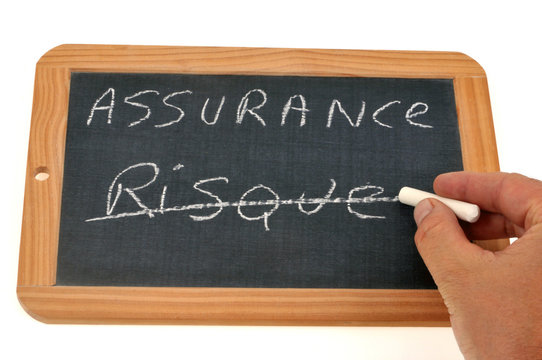 Homme barrant le mot risque sur une ardoise o&ugrave; il y a le mot assurance &eacute;crit