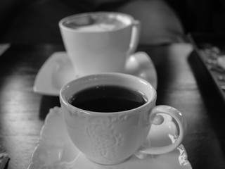 White cup of coffee on the wooden table in cafe restaurant . Black and White picture