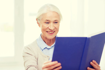 Fototapeta na wymiar happy smiling senior woman reading book at home