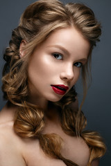 Fototapeta premium Beautiful girl with braids and gentle makeup. Nude. Beauty model with bright red lips. Beautiful face. The photo was taken in studio 