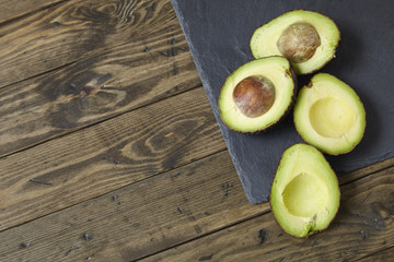 Halved avocados on a slate and distressed wooden kitchen counter background forming a page frame