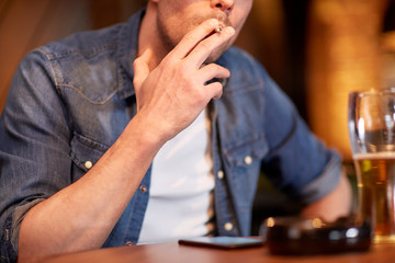 man drinking beer and smoking cigarette at bar