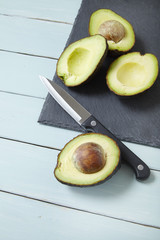 Halved avocados on a chopping board with a sharp knife, on a painted counter top background © beckystarsmore