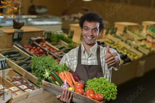 "Grocery clerk working in produce aisle of supermarket store" photo