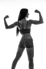 Athletic young woman showing muscles of the back and hands. Black and white.